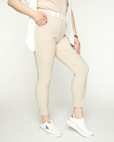 Royalfashion Beżowe damskie spodnie materiałowe z napisem PLUS SIZE