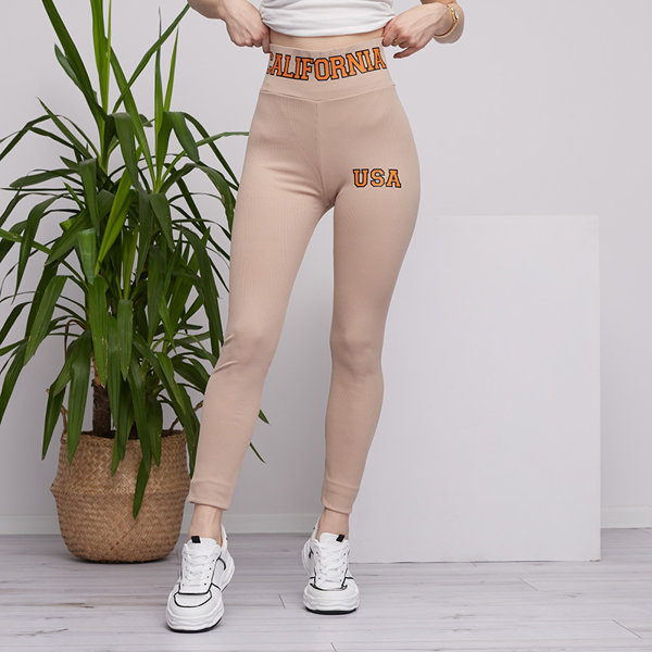 Royalfashion Beżowe damskie prążkowane legginsy z pomarańczowymi napisami